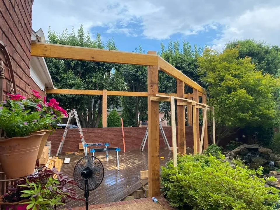 Timber framing for a new patio cover going up beside a brick home