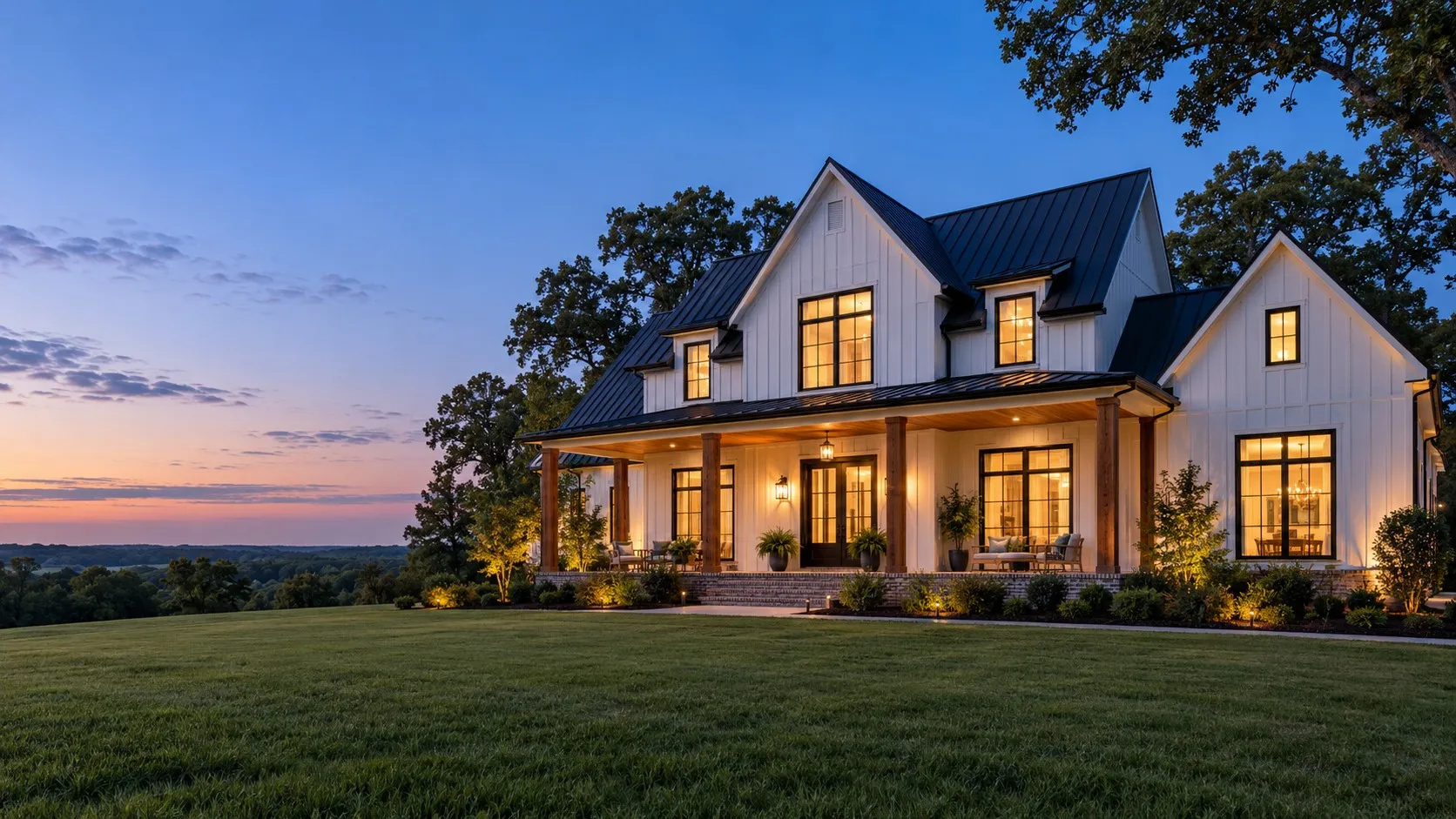 A white farmhouse-style custom home with a lit front porch at dusk